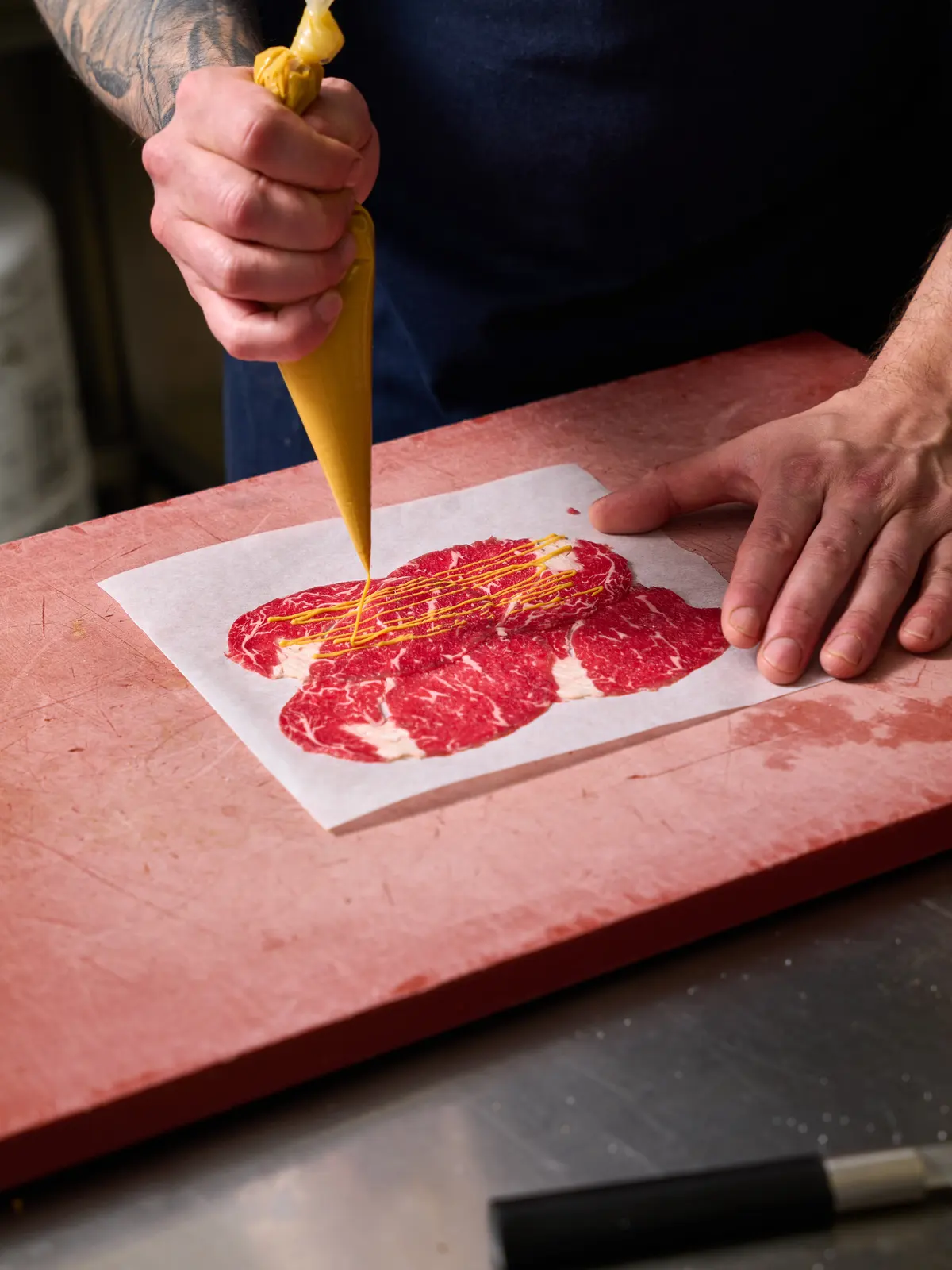 Preparing beef carpaccio with sauce.